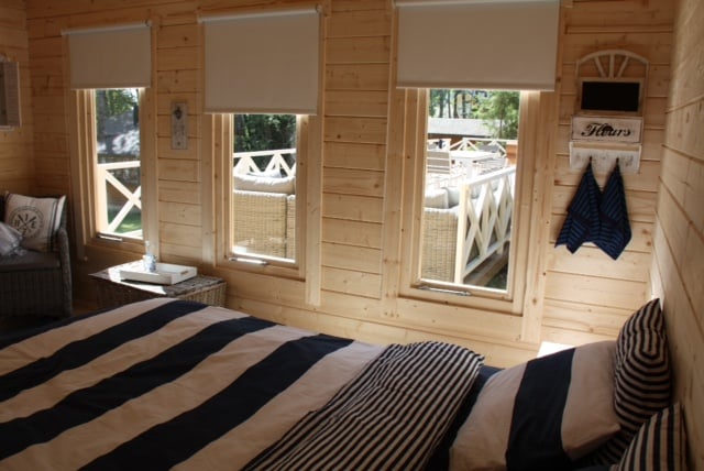 log cabin bedroom interior view with three windows and bed