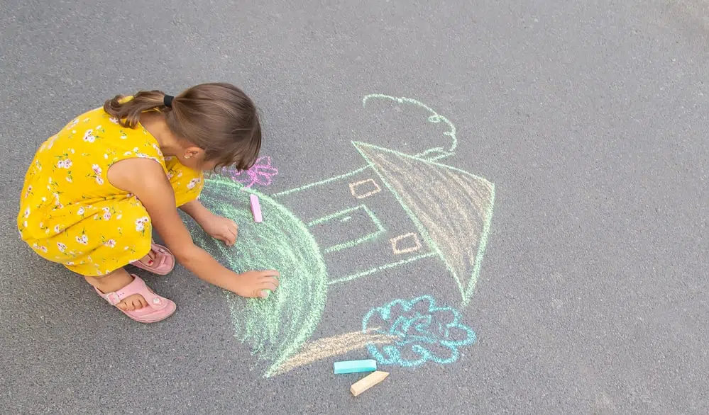 a small girl drawing on the pavement