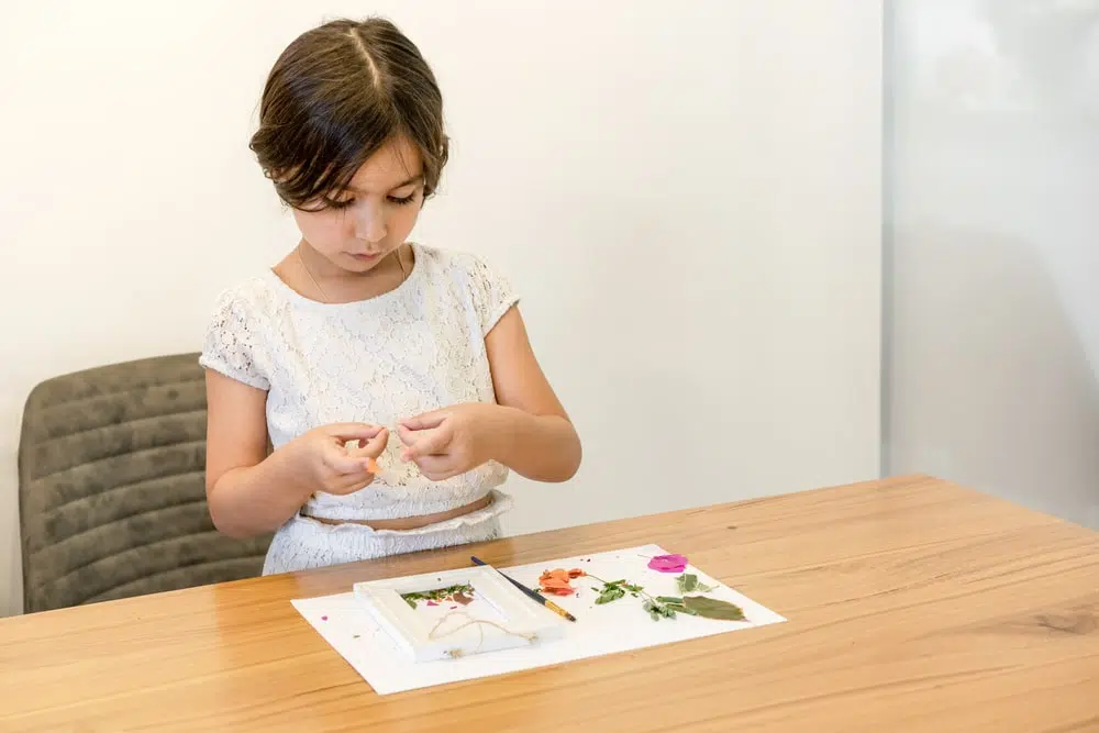 a small girl making art from dry flowers