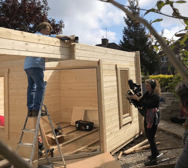 Two people assembling a wooden summer house