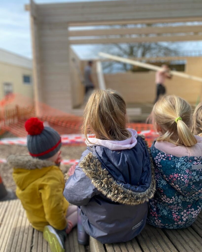 children watching log cabin being built