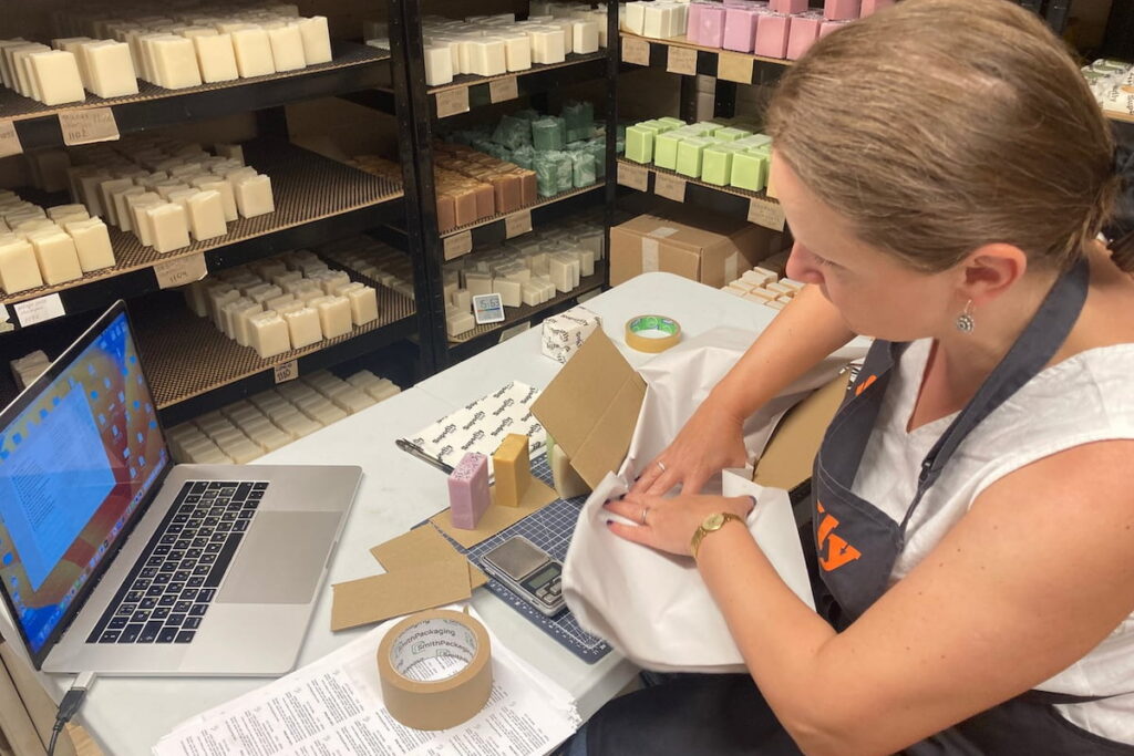 female business owner packaging products at desk