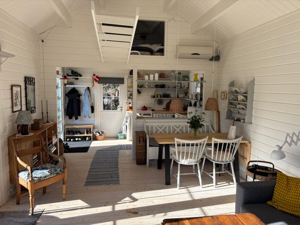 Summerhouse interior with mezzanine sleeping loft, dining table, and open-plan kitchen area