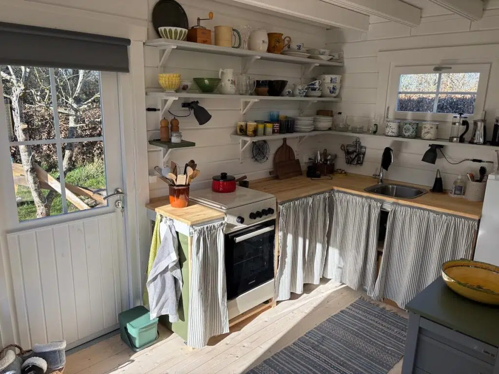 Summerhouse kitchen with open shelving, freestanding cooker, butcher-block worktop